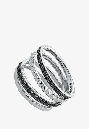 Conjunto de tres anillos entrelazados, de metal plateado, con acentos de gema negra y un patrón geométrico texturizado en una de las bandas.
