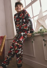 Sort pyjamasæt med farverige julemotiver, herunder rensdyr og snefnug. Blødt stof med lange ærmer og elastisk talje.
