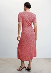 Rode bloemen midi-jurk met korte puffmouwen, getailleerde lijfje en vloeiende rok. Draag met zwarte sandaaltjes met bandjes, gladde stof en een lichte glans.