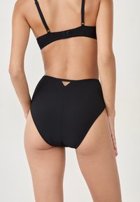 Costume da bagno a vita alta nero con dettaglio a chiave sul retro, realizzato in tessuto liscio e elasticizzato. Presenta un design senza cuciture.