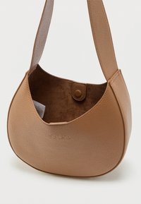 Τσάντα ώμου από δέρμα με υφή καμήλας, με φαρδιά λουρίδα, ανοιχτό πάνω μέρος, κλείσιμο με κουμπί και μαλακή σουέτ εσωτερική επένδυση που περιέχει διπλωμένο χαρτί.