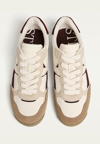 Baskets avec une tige en cuir blanc, des accents en suède beige clair et une bande bordeaux. Présentent des lacets blancs et un col rembourré.