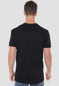 Schwarzes Baumwoll-T-Shirt mit kurzen Ärmeln und Rundhalsausschnitt, das eine glatte Textur und ein einfaches Design ohne Logos oder Muster zeigt.