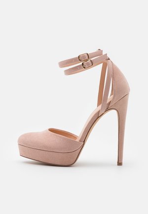 Różowy szpilka łososiowy z zamszową fakturą, z platformą z przodu oraz dwoma cienkimi paskami przy kostce z regulowanymi złotymi klamrami.