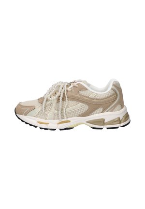Beiger und cremefarbener Sportschuh mit Mesh- und Wildlederpaneelen, schwarzer Sohle und einer klaren Perlenkette, die über die Schnürsenkel drapiert ist, auf weißem Hintergrund.