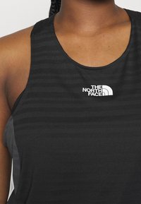 Zwarte mouwloze sporttop met een gestructureerd patroon en logo van The North Face op de borst. Ronde halslijn en aansluitend design.