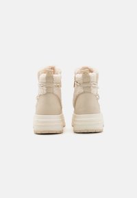Béžové kotníkové boty s měkkým texturovaným svrškem, hladkou koženou zádou a silnou bílou podrážkou. Obsahují boční zipy a textilní detaily.