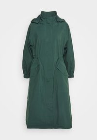 Dlouhý, tmavě zelený nepromokavý kabát s vysokým límcem, stáhnutým pasem a dvěma bočními kapsami. Hladká textura, elastické manžety a délka po kolena.