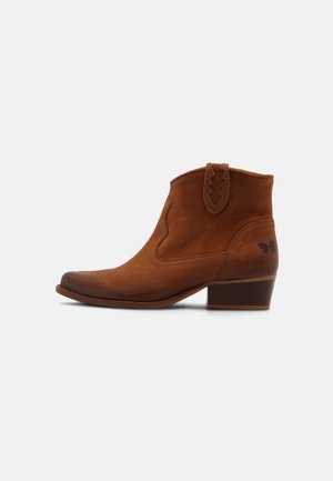 Botines de cuero marrón con punta puntiaguda, costuras decorativas y tacón bajo apilado; incluyen una lengüeta para tirar y detalles sutiles con patrones.