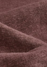 Tkany materiał w miękkim, stonowanym kolorze mauve z drobnym, teksturowanym splotem. Subtelna głębia tworzona przez falujące zagięcia w tkaninie.