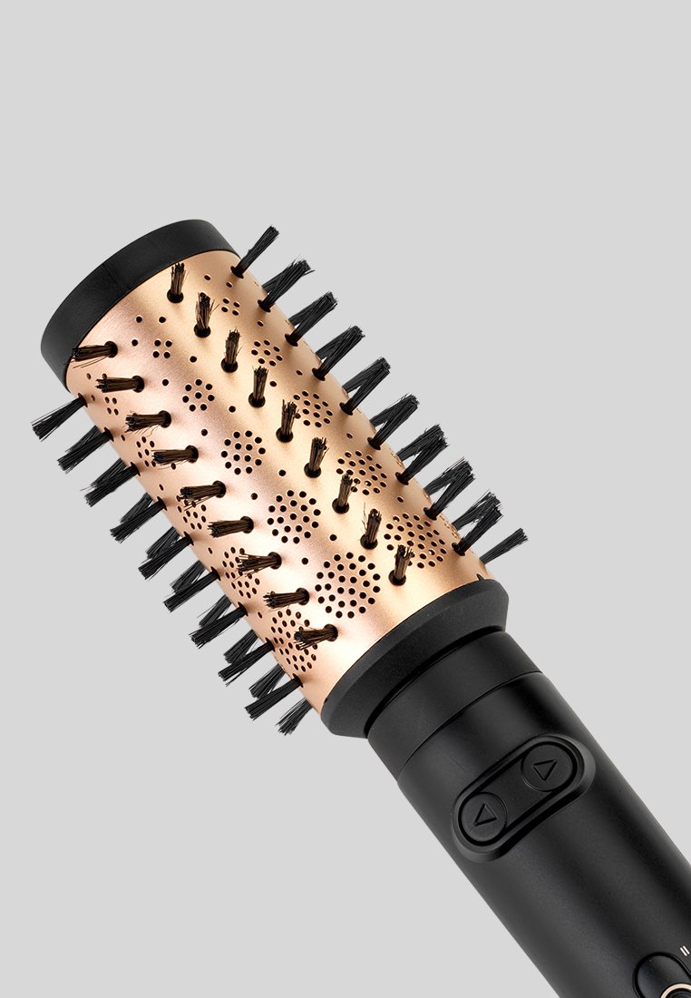Brosse à cheveux ronde avec un baril en métal rose doré et un manche en plastique noir, dotée de poils et de trous de ventilation sur sa surface.