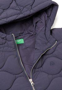 Námořnická prošívaná puffer bunda s kapucí, vybavená kovovým zipem a zelenou nálepkou uvnitř. Tkanina vypadá hladce a lehce.