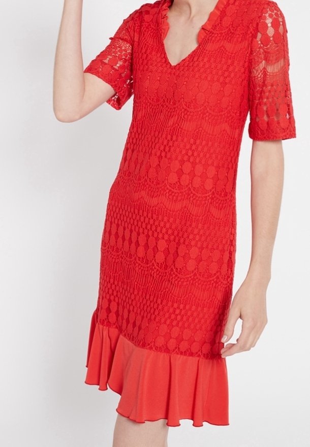Červené krajkové šaty s krátkými rukávy, výstřihem do V a vlnitým lemem. Obsahují texturované vzory a vyztuženou volánkovou sukni na spodní části.