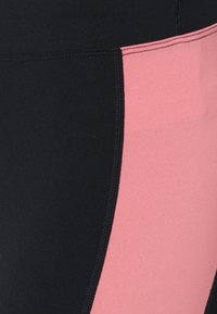 Black and pink leggings featuring a smooth fabric with a color block design, showcasing a black section and a pink panel with flat seams.