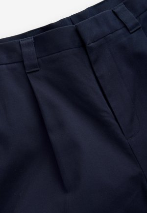 Marineblå plisserede bukser med en glat, struktureret stof. Har en flad talje og bæltestropper, designet til komfort og pasform.