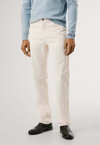 Pantaloni in corduroy beige chiaro a gamba dritta, con tasche frontali, chiusura con bottone e abbinati a stivali neri eleganti.