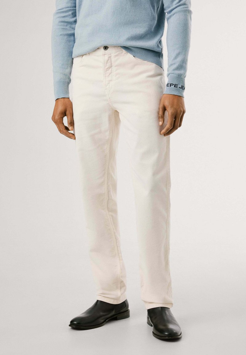 Pantaloni in corduroy beige chiaro a gamba dritta, con tasche frontali, chiusura con bottone e abbinati a stivali neri eleganti.