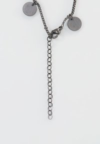 Kettenhalskette mit dunklen Metallgliedern, ausgestattet mit zwei runden Anhängern und einem langen, hängenden Kettenabschnitt.