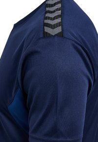 Nahaufnahme eines marineblauen Sportshirts mit schwarzer und grauer Chevron-Musterung an der Schulter.