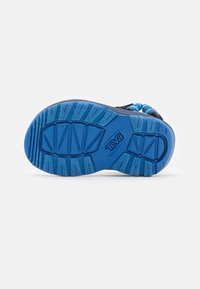 Teva sandal såle i blå gummi med et teksturert grep mønster. Har en hevet logo og konturer av sålen for bedre grep.