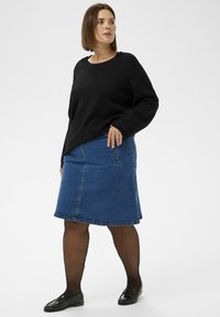 Fekete pulóver kerek nyakkivágással, világoskék farmer szoknyával párosítva. A szoknya egyenes szabású, finom varrási részletekkel. Fekete loaferek teszik teljessé az öltözéket.