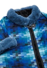 Cămașă în carouri albastre cu un guler și manșete din blană sintetică, cu un fermoar negru și o textură moale. Culorile predominante includ albastru închis și turcoaz.