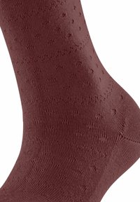 Braune, gemusterte Socke aus strukturiertem Stoff, die kleine sternartige Designs und gerippte Details aufweist und eine glatte Oberfläche betont.