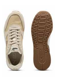 Beige sportsko med en mesh-overdel, ruskinds overlays og en struktureret gummisål. Har logo-detaljer og et traditionelt snøresystem.