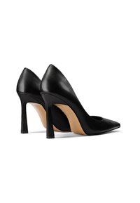Tacchi alti in pelle nera con punta affusolata e tacco a forma stretta. Texture liscia, design minimalista, con una suola beige a contrasto.