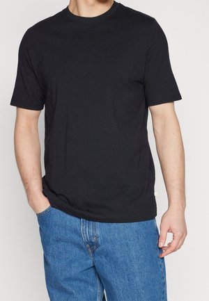 T-shirt en coton noir avec col rond, manches courtes et coupe décontractée. Présente une texture lisse et un détail de couture subtile à l'ourlet.