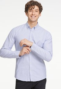 Blå och vit randig skjorta med knappar, krage, långa  ärmar och knappmanchetter. Tillverkad av ett lätt tyg, med en skräddarsydd passform.
