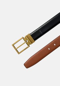 Tweekleurige riem met een zwarte leren band en een bruine, getextureerde band, voorzien van een rechthoekige gesp van goudkleurig metaal.