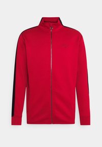 Chaqueta roja con cremallera y alto cuello, de mangas largas y con acentos negros en los hombros. Presenta un logo en el pecho y tela suave y texturizada.