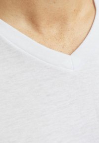 Weißes V-Ausschnitt-T-Shirt aus weichem, leichtem Stoff. Verfügt über einen gerippten Kragen und ein einfaches, sauberes Design mit einer glatten Textur.