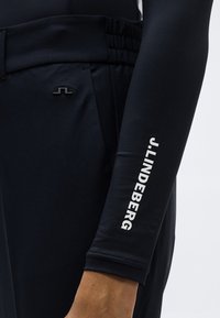 Μπλούζα μακρυμάνικη σε ναυτικό μπλε με εφαρμοστή γραμμή, διαθέτει ελαστικά μανσέτα και λευκή εκτύπωση λογότυπου στο μανίκι, κατασκευασμένη από απαλό ύφασμα.