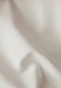 Glattes, hellbeiges Gewebe mit einem subtilen Glanz. Es hat eine feine Rippstruktur und einen weichen Fall, was Vielseitigkeit für verschiedene Anwendungen suggeriert.