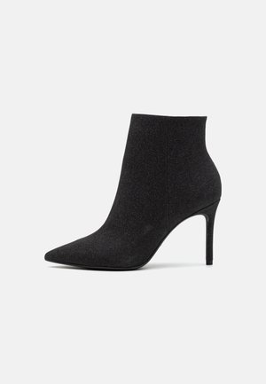 Bottines noires à bout pointu, fabriquées en tissu texturé. Elles présentent un talon aiguille et une silhouette élégante et épurée.
