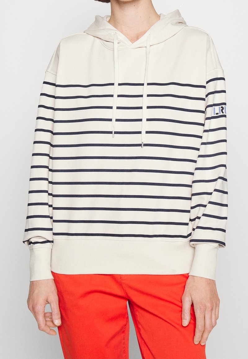 Crèmekleurige hoodie met marineblauwe horizontale strepen, capuchon met trekkoord en geribbelde zoom. Voorzien van een logo-embleem op de linkermouw, ontspannen pasvorm.