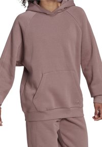 Przestronna bluza z kapturem w stonowanym odcieniu mauve. Wykonana z miękkiego materiału, z ściągaczami na rękawach i dużą kieszenią z przodu. Oferuje subtelną detalizację logo.