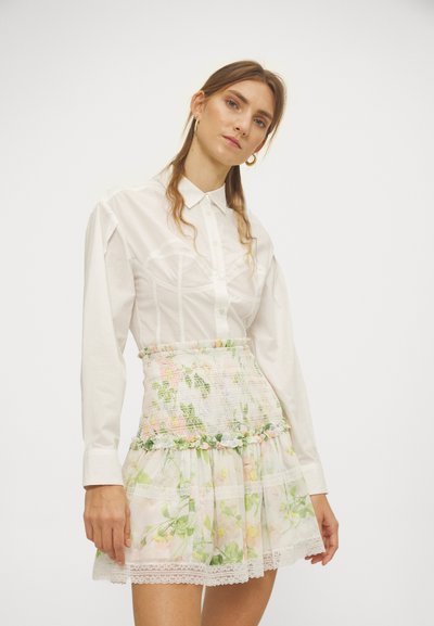 Hvit langermet skjorte med knappelukking og mini skjørt med blomsterdesign i lag, som har pastellfarger og blonder.