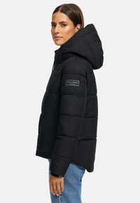 Black puffer jacket with a hood, featuring a quilted design, logo patch on the sleeve, and zippered side pockets.