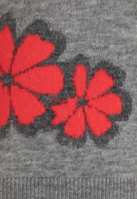 Grijze stof met een bloemenpatroon met grote rode bloemen omrand door zwart, met een zachte gebreide textuur.