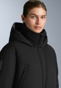 Czarna kurtka puchowa z wysokim kołnierzem, z zamkiem błyskawicznym z przodu i zasuwanymi kieszeniami bocznymi. Gładka tekstura materiału, nowoczesny design.