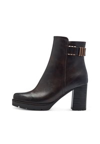 Botte en cuir marron arrivant à la cheville avec un talon épais, un bout arrondi et une semelle texturée. Comprend un accent métallique décoratif à la cheville.