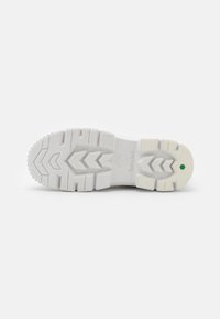 Semelle en caoutchouc blanc avec des motifs de bande de roulement profonds, montrant le logo Timberland et un petit hexagone vert près du talon.