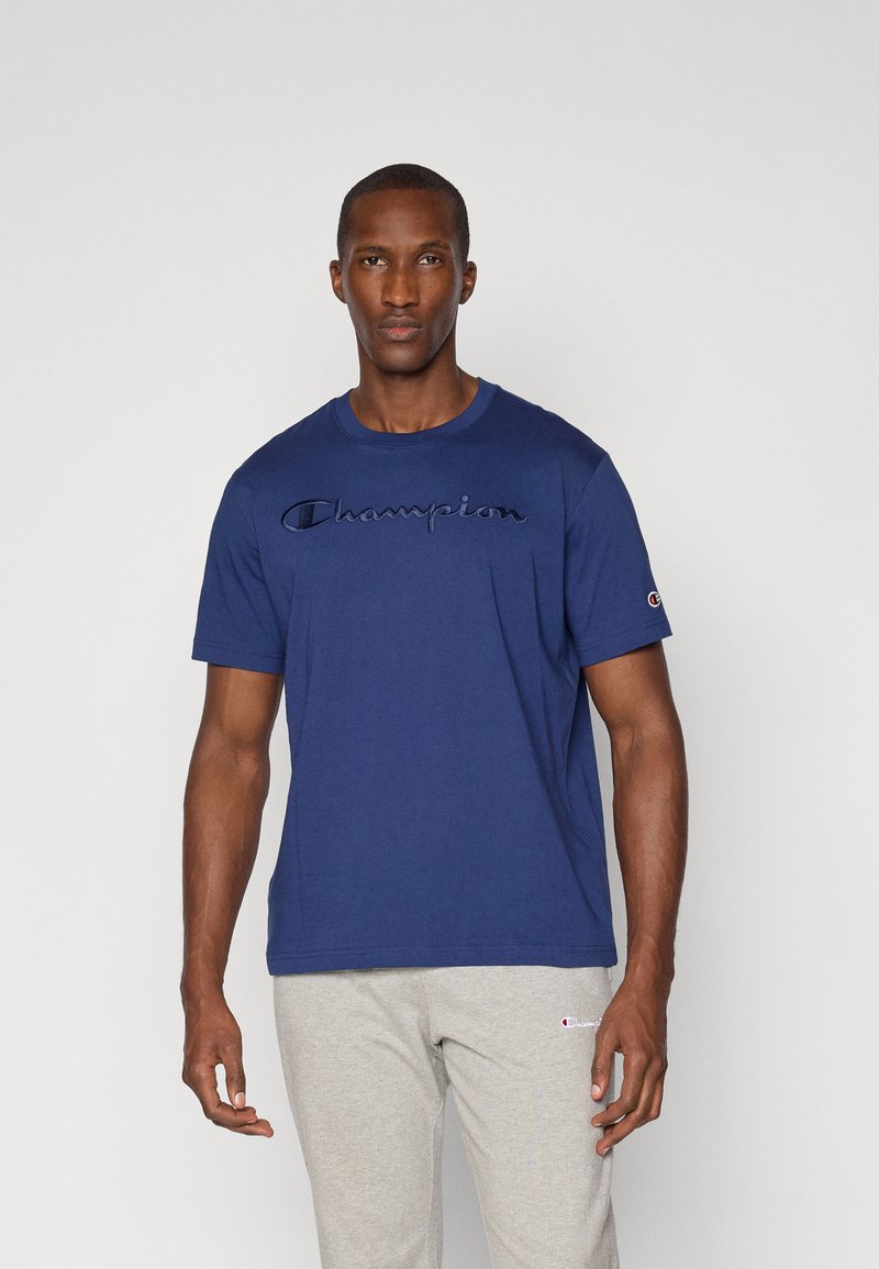 Navyblaue Baumwoll-T-Shirt mit einem gestickten "Champion"-Logo auf der Brust. Kurze Ärmel, Rundhalsausschnitt, normale Passform.