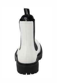 Bottine blanche et noire avec semelle épaisse noire, languette arrière avec texte blanc, coutures visibles.