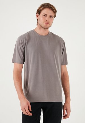 Tricou scurt gri, cu mânecă scurtă, fabricat dintr-un material neted și ușor. Are un guler rotund și o croială lejeră, fără modele vizibile.