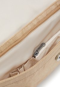 Beige stoftas med en glat tekstur, der har en lynlås lomme og indvendige rum til organisering. Lysebrun foret supplerer udsiden.