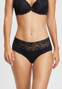 Culotte noire avec une ceinture en dentelle à motifs floraux, tissu lisse et bords festonnés. Design classique.